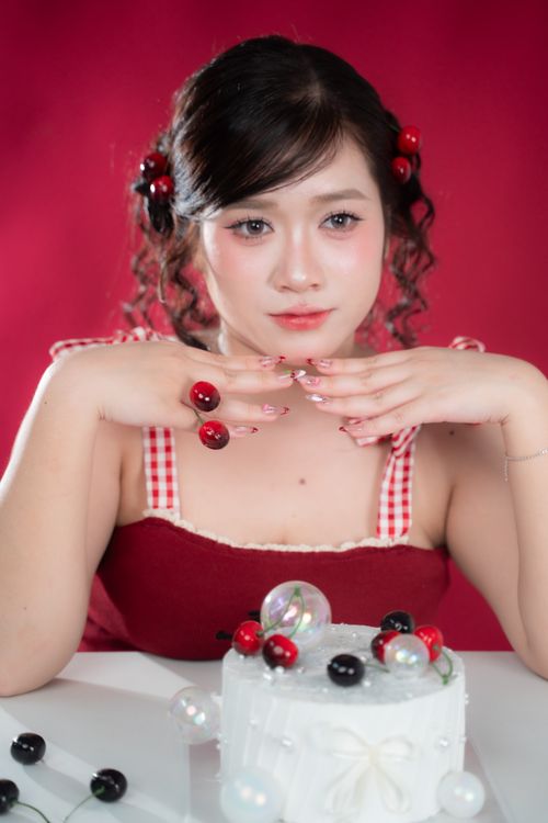 Free Portrait of a woman with cherry-themed styling posing with a decorated cake. Stock Photo