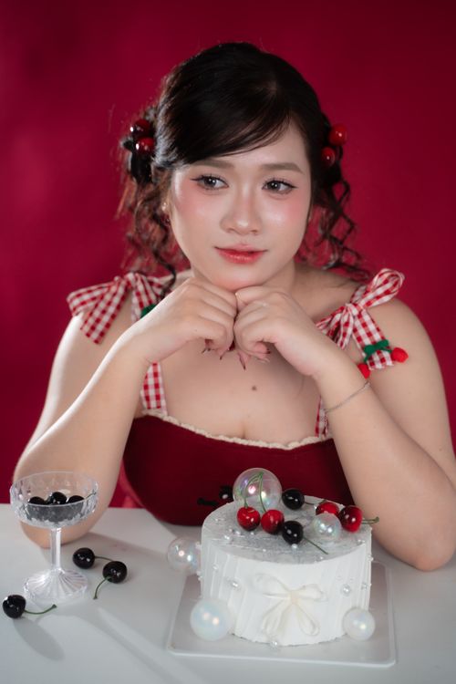 Free Young woman in a red dress with a cherry cake, creating a festive and joyful atmosphere. Stock Photo