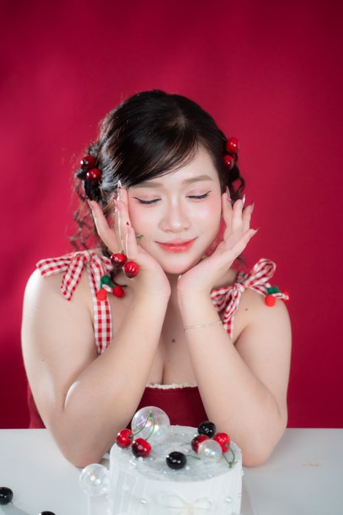 Free Smiling woman with cherry accessories enjoying a cake indoors. Stock Photo