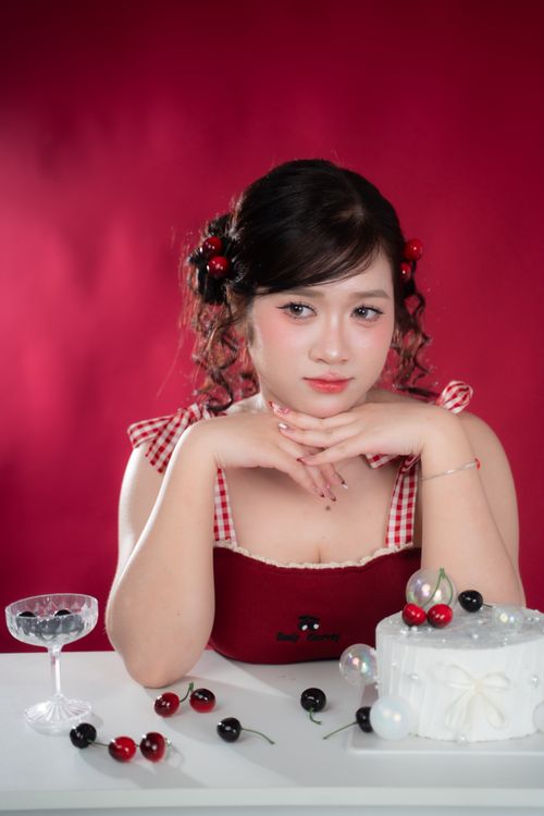 Free Woman in red dress posing with cherry-themed cake, exuding elegance. Stock Photo