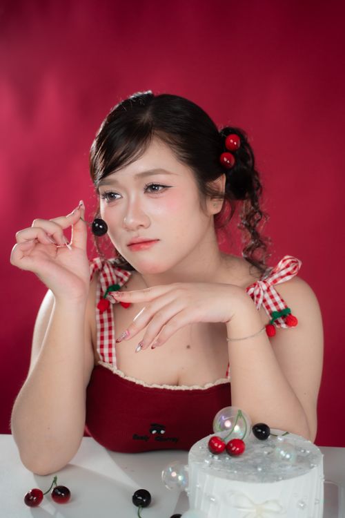 Free Elegant woman in red dress with cherries, posing in a studio with a cake. Stock Photo