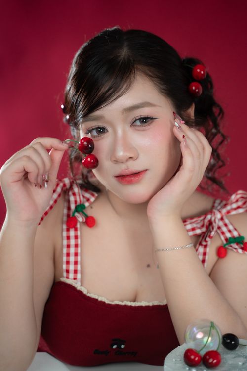 Free Woman with cherry-themed fashion posing indoors on red background. Stock Photo