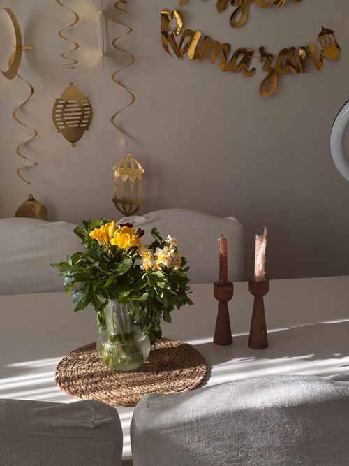 Free A decorative table setup for Ramadan featuring flowers and candles in a cozy home setting. Stock Photo