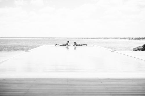 Free Serene scene at an infinity pool with two women relaxing, ocean in view. Stock Photo