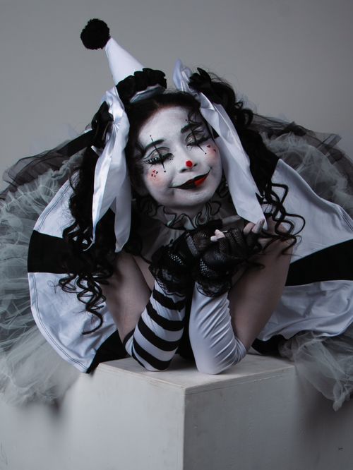 Free A dramatic portrait of a person in a monochrome clown costume, showcasing theatrical makeup and attire. Stock Photo