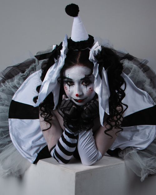 Free Dramatic portrait of a clown in black and white makeup with striped costume, evoking emotion and artistry. Stock Photo