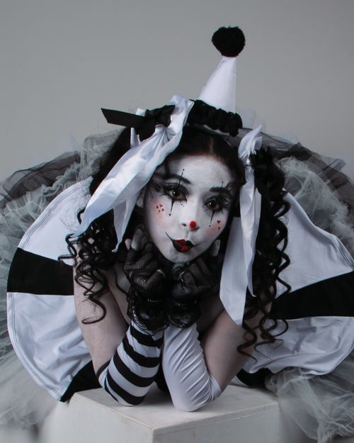 Free An artistic studio portrait of a person wearing a Pierrot costume with dramatic makeup and black-and-white attire. Stock Photo