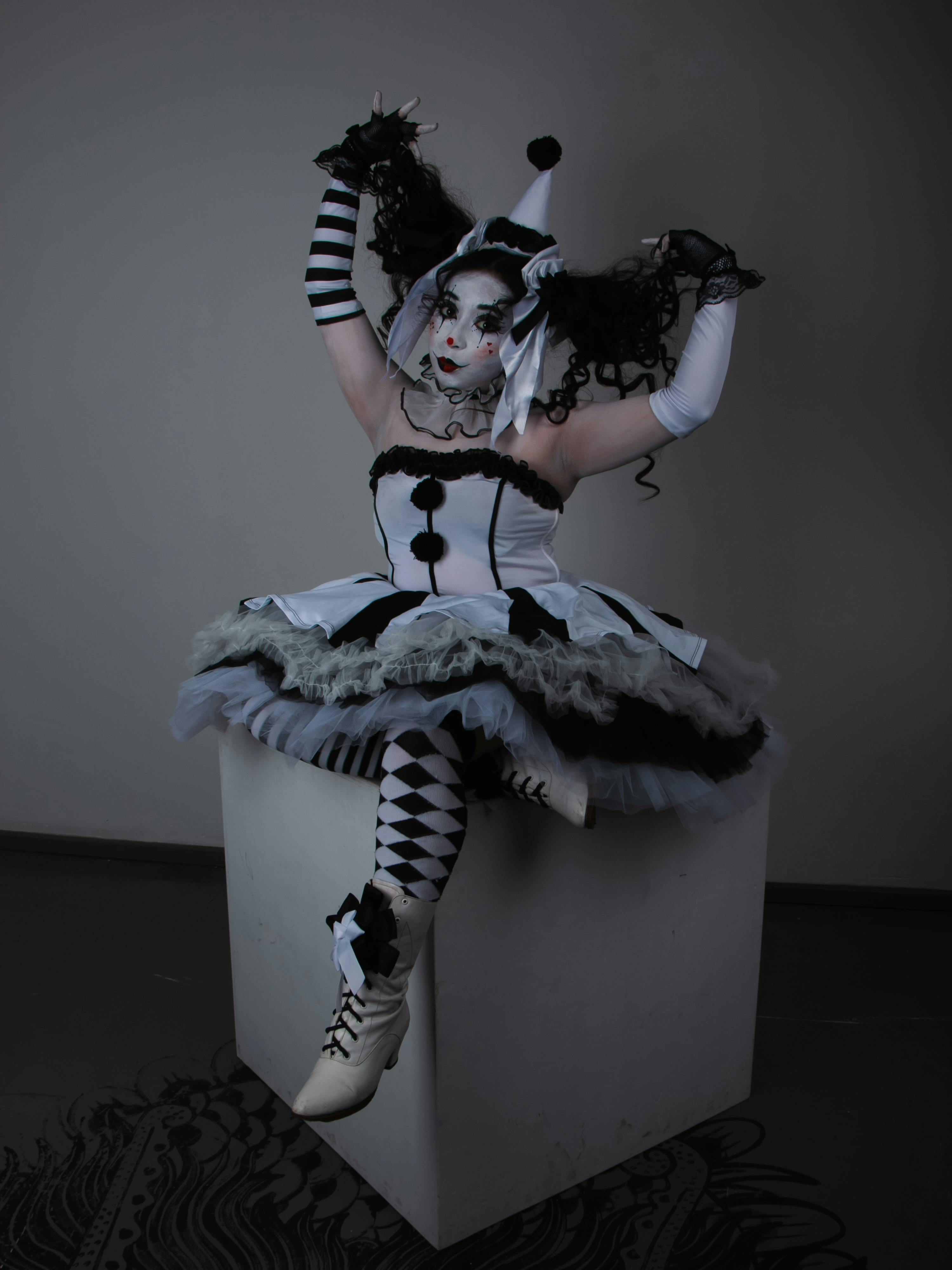 Free Artistic portrayal of a harlequin performer in a theatrical black and white costume. Stock Photo