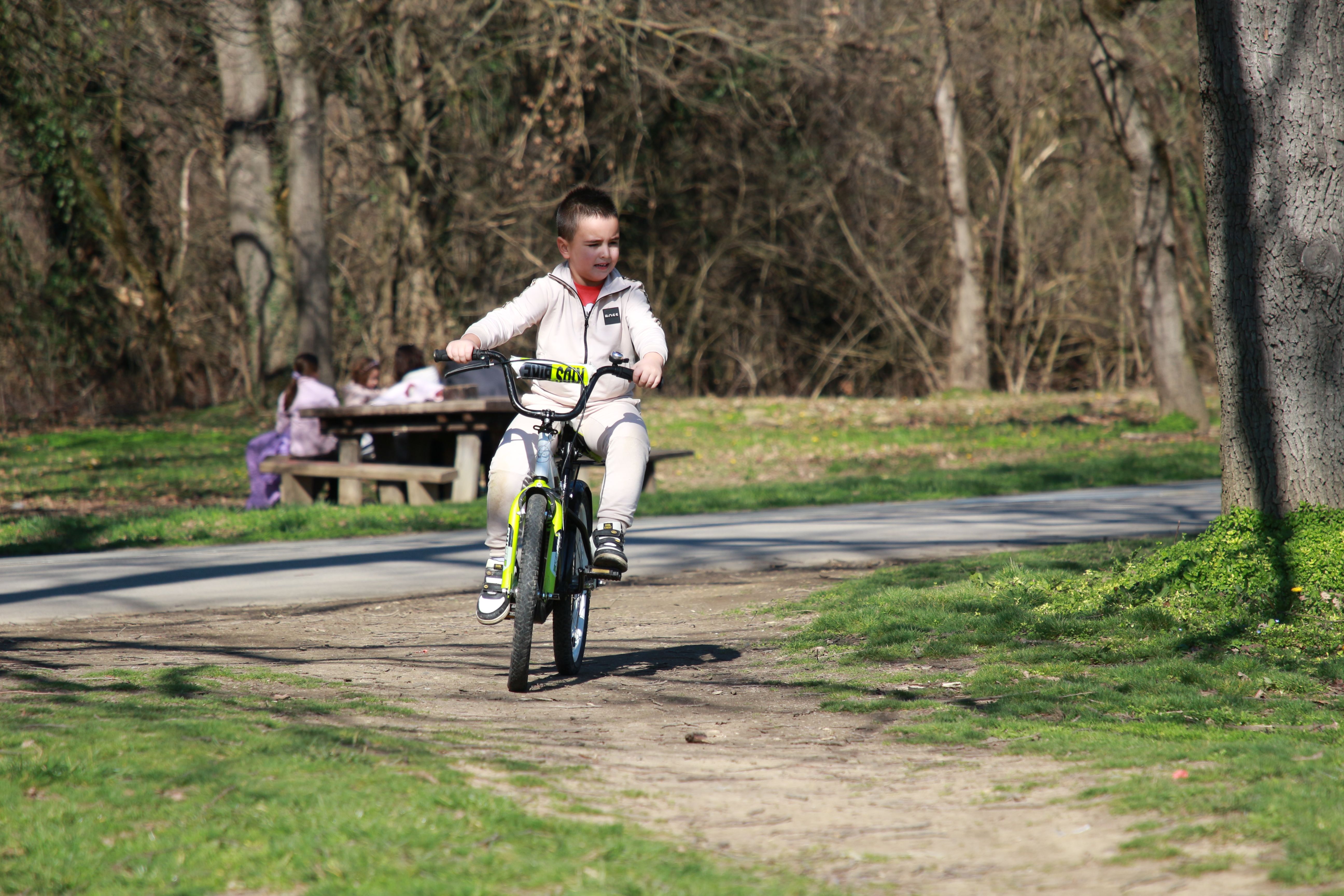 A young boy joyfully rides a bicycle on a sunny day in the park.