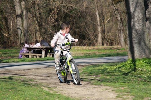 Young boy cycling on a pathway in a quiet park during a sunny day.