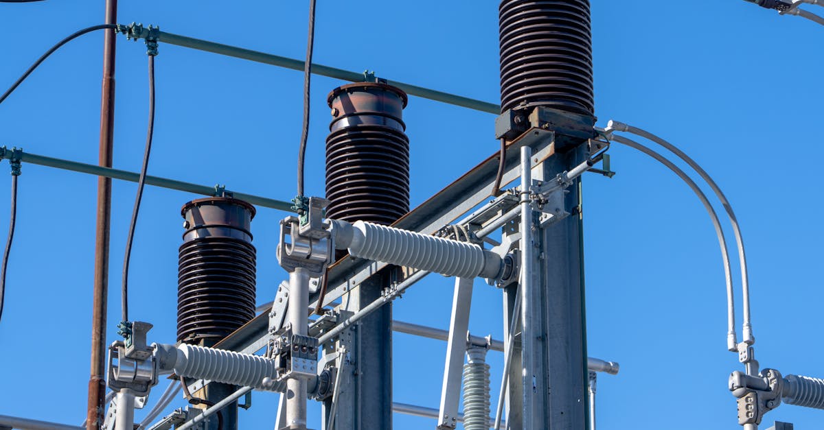 Photo by Phil Evenden Detailed view of electrical components in a power substation under a clear blue sky.