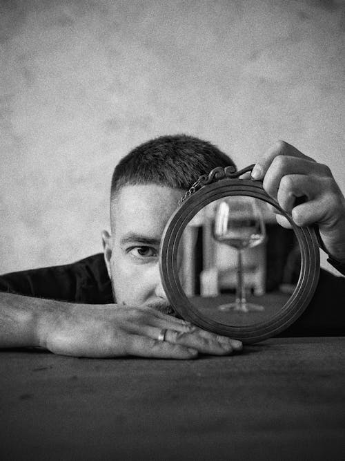 Foto Em Tons De Cinza De Um Homem Segurando Um Espelho Redondo