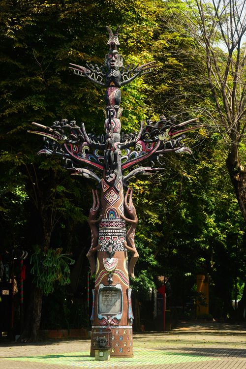 Free Vibrant tribal totem in a lush green park setting under bright sunlight. Stock Photo