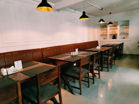 Comfortable and stylish cafe interior with brown leather seating and wooden tables under warm lighting.