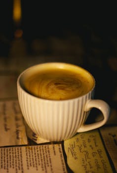 A close-up of a cappuccino in a ridged ceramic cup on a dimly lit café table with a relaxed ambiance.