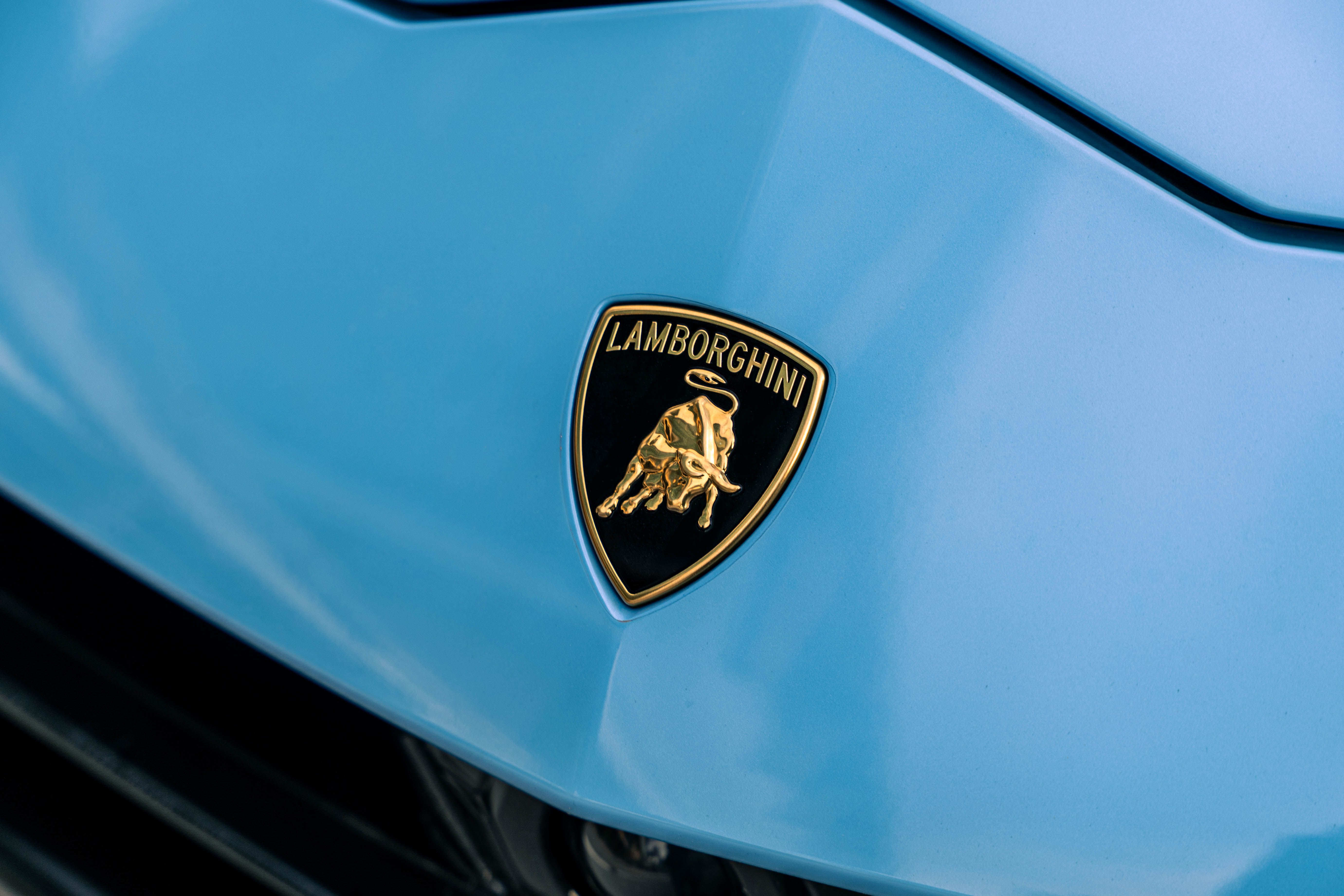 Detailed shot of Lamborghini badge on a sleek blue car hood, showcasing luxury and design.