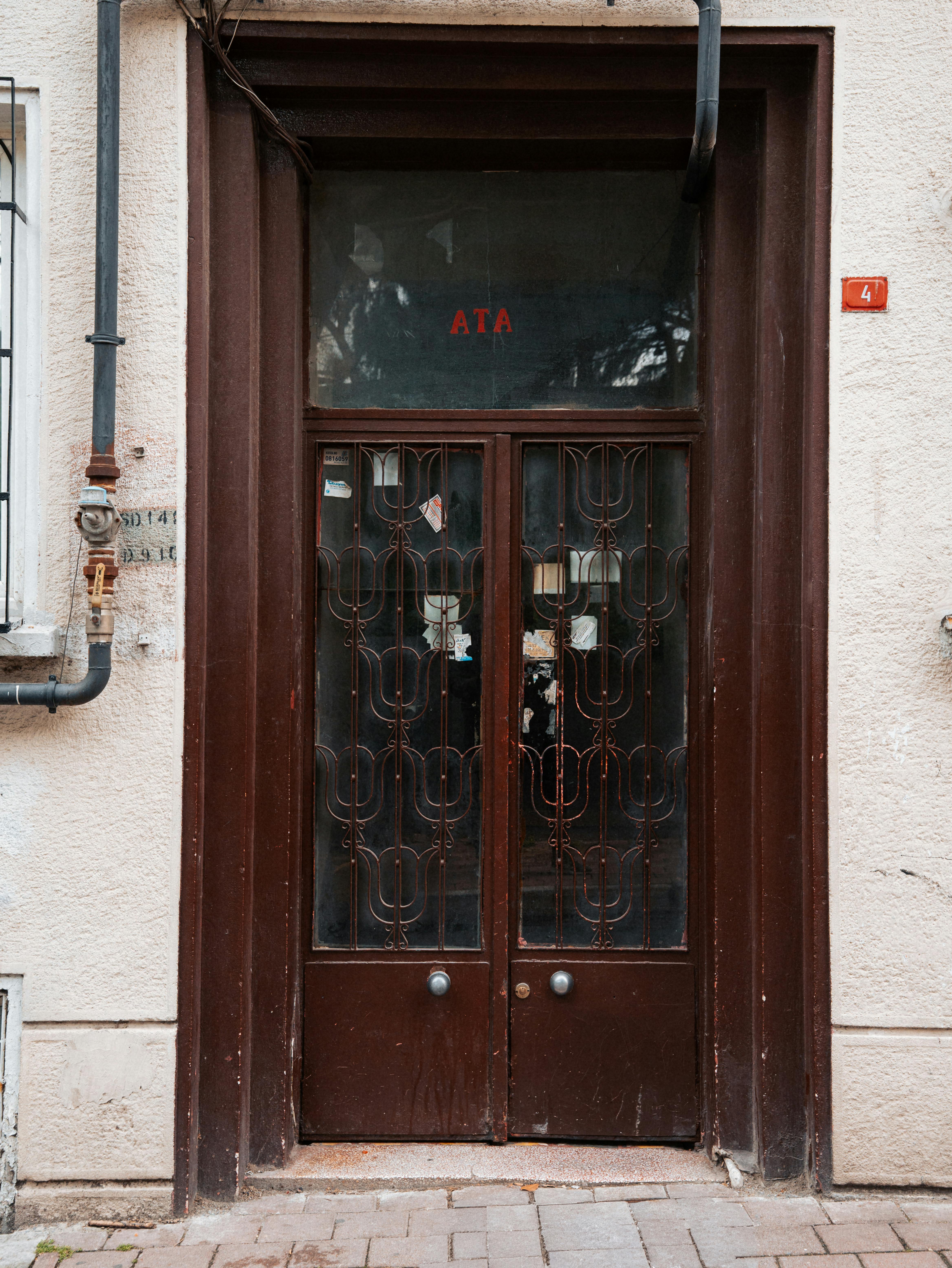 бесплатная Вид спереди классической коричневой двери со сложной металлической решеткой в ​​городской среде — идеальный вариант для архитектурных тем. Стоковое фото