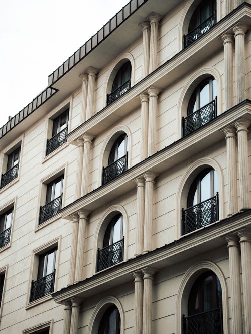 Free Capture of a neoclassical building facade with arched windows and columns, highlighting urban architectural elegance. Stock Photo