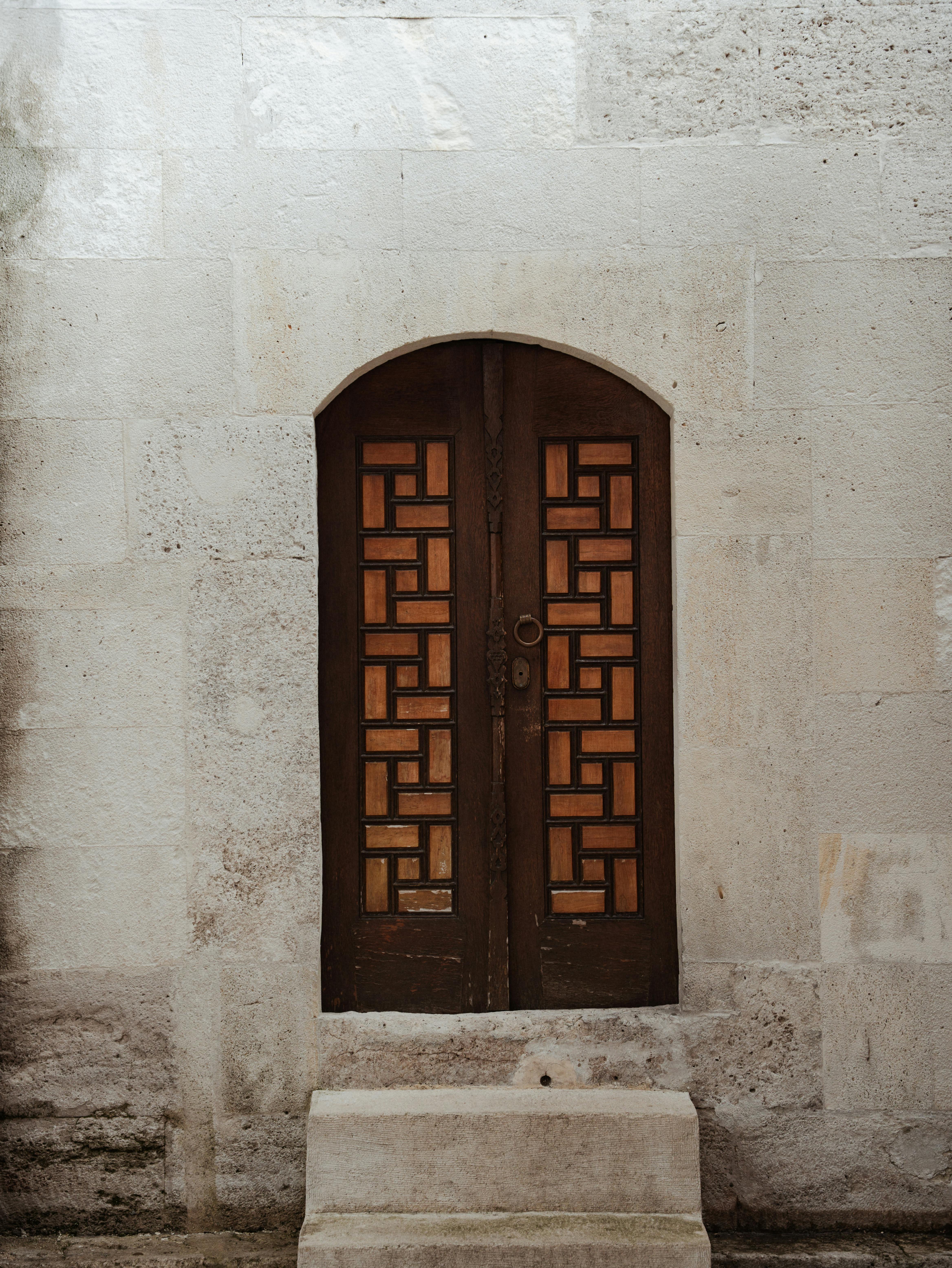 無料 石造りの建物の正面に、複雑な錬鉄の模様が施された古い木製のドア。 写真素材