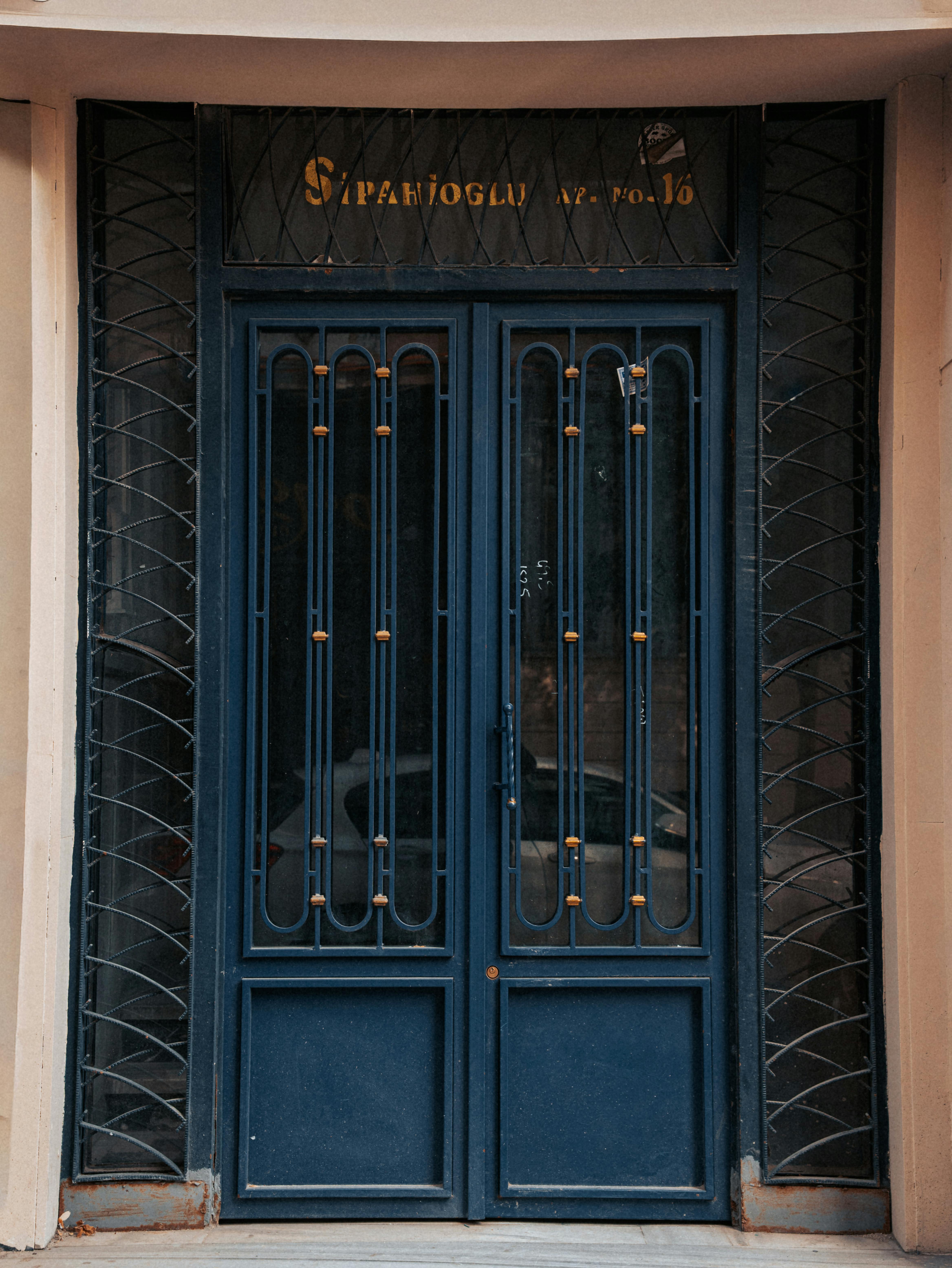 無料 伝統的な建物のファサードに、複雑な鉄細工が施されたビンテージの青いドア。 写真素材