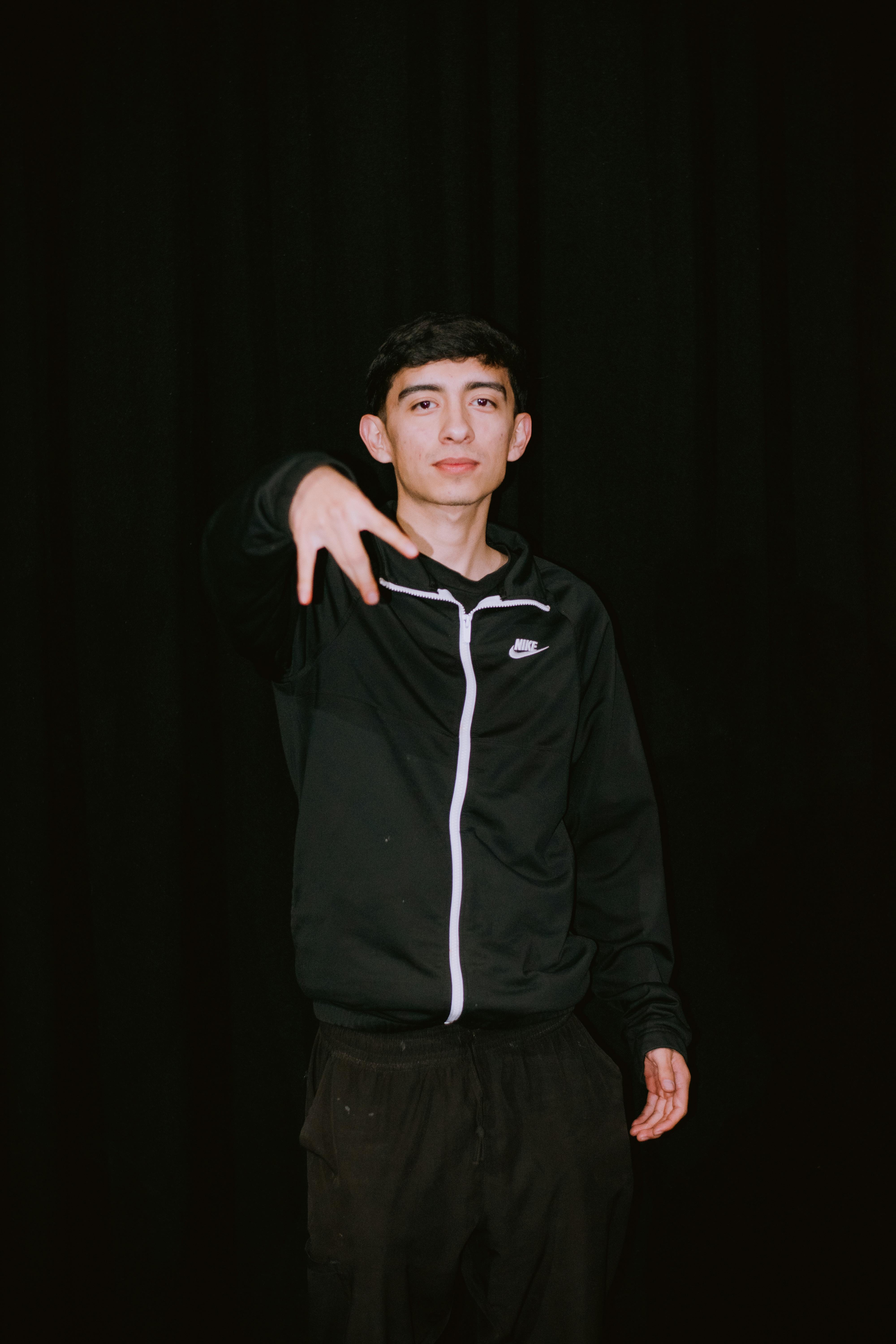 Free Portrait of a young man in a black tracksuit posing with confidence against a dark background Stock Photo