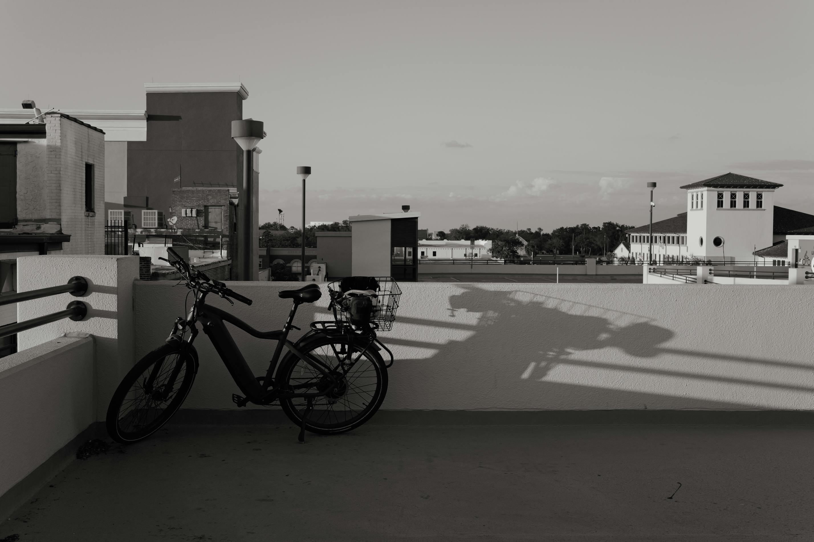 無料 夕暮れ時の都市のスカイラインを背景にした自転車のシルエット。近代建築が映えます。 写真素材