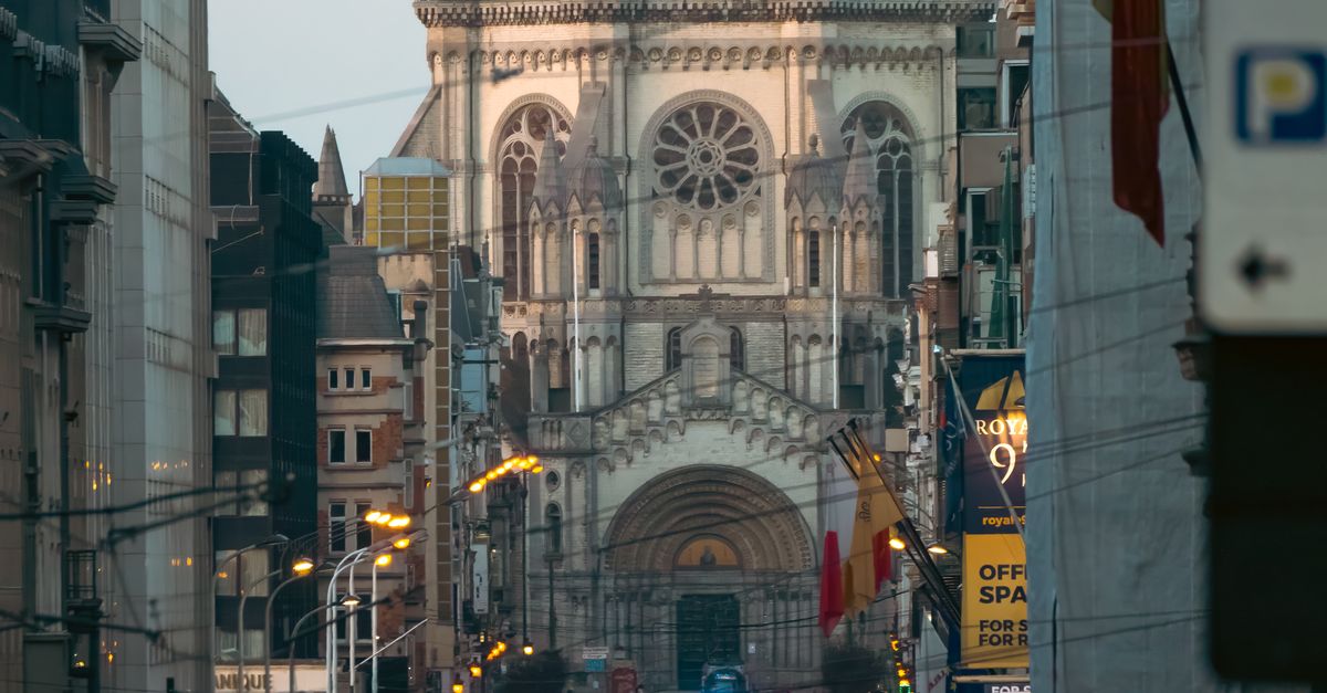 Busy street in Brussels with Church of St. John and St. Stephen in the backdrop.