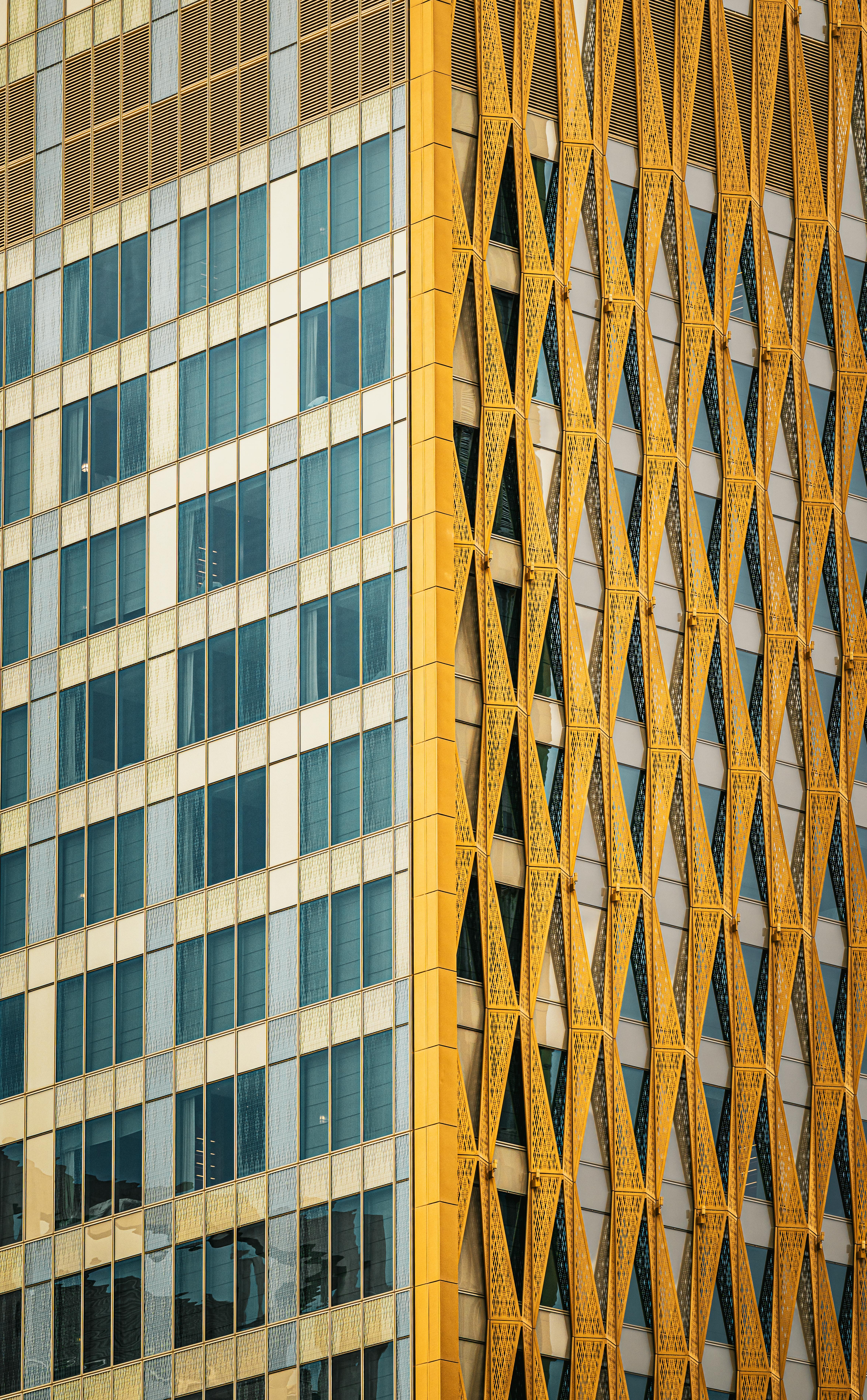 Gratuit Détail architectural dynamique de la façade d'un immeuble de grande hauteur à Koweït City, orné d'un motif en treillis doré. Photos