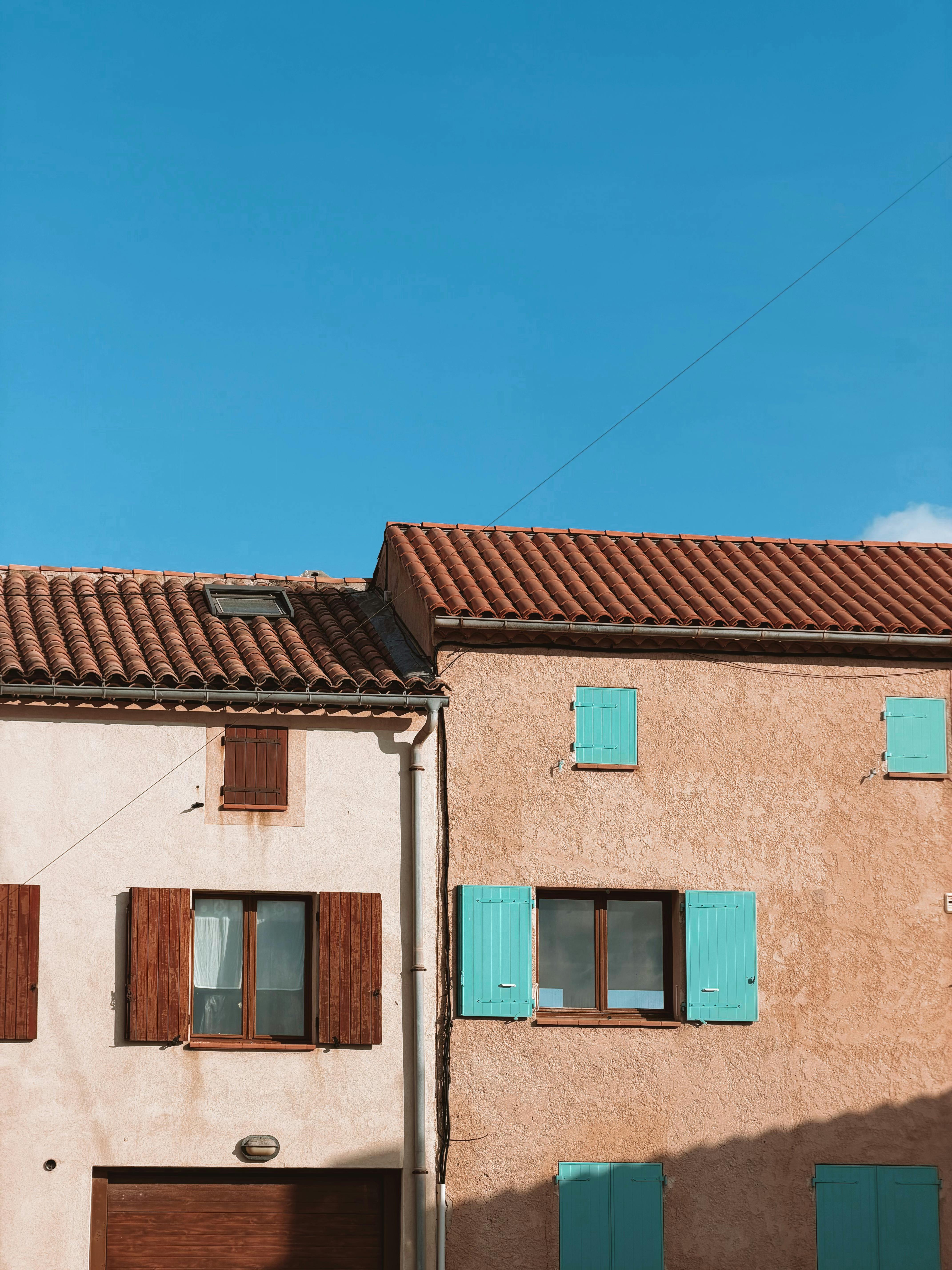 無料 澄んだ青い空を背景に、色鮮やかなシャッターが付いた素朴な地中海の家々。 写真素材