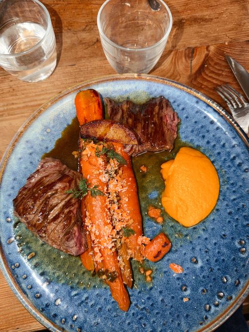 Free Delicious steak with glazed carrots and puree served on a blue plate. Stock Photo