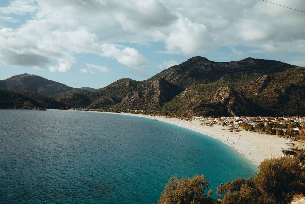 Plaja și laguna de la Ölüdeniz, în Turcia, cu munți în fundal și apă turcoaz