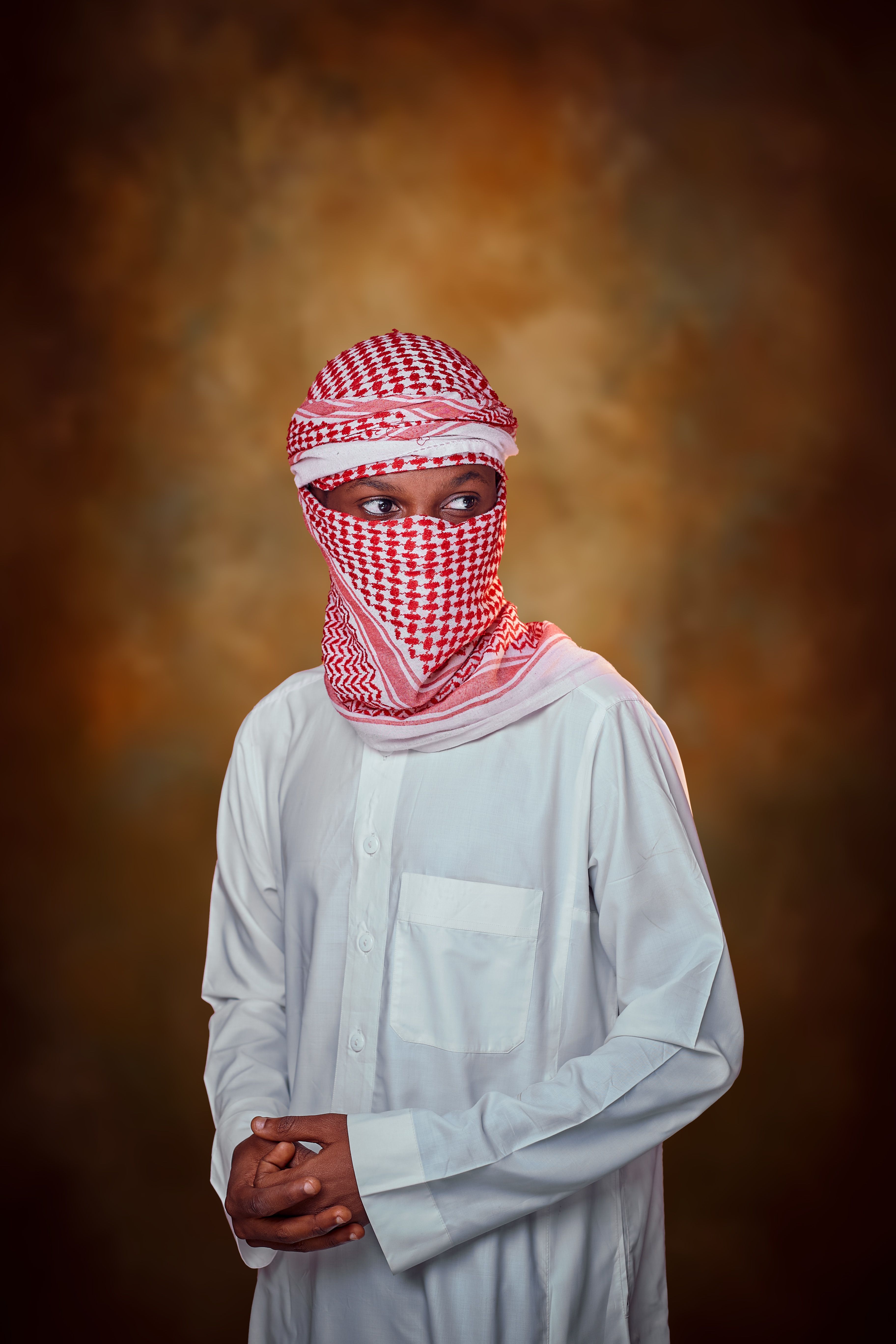 Man in traditional Middle Eastern attire with a keffiyeh and white robe, looking sideways.