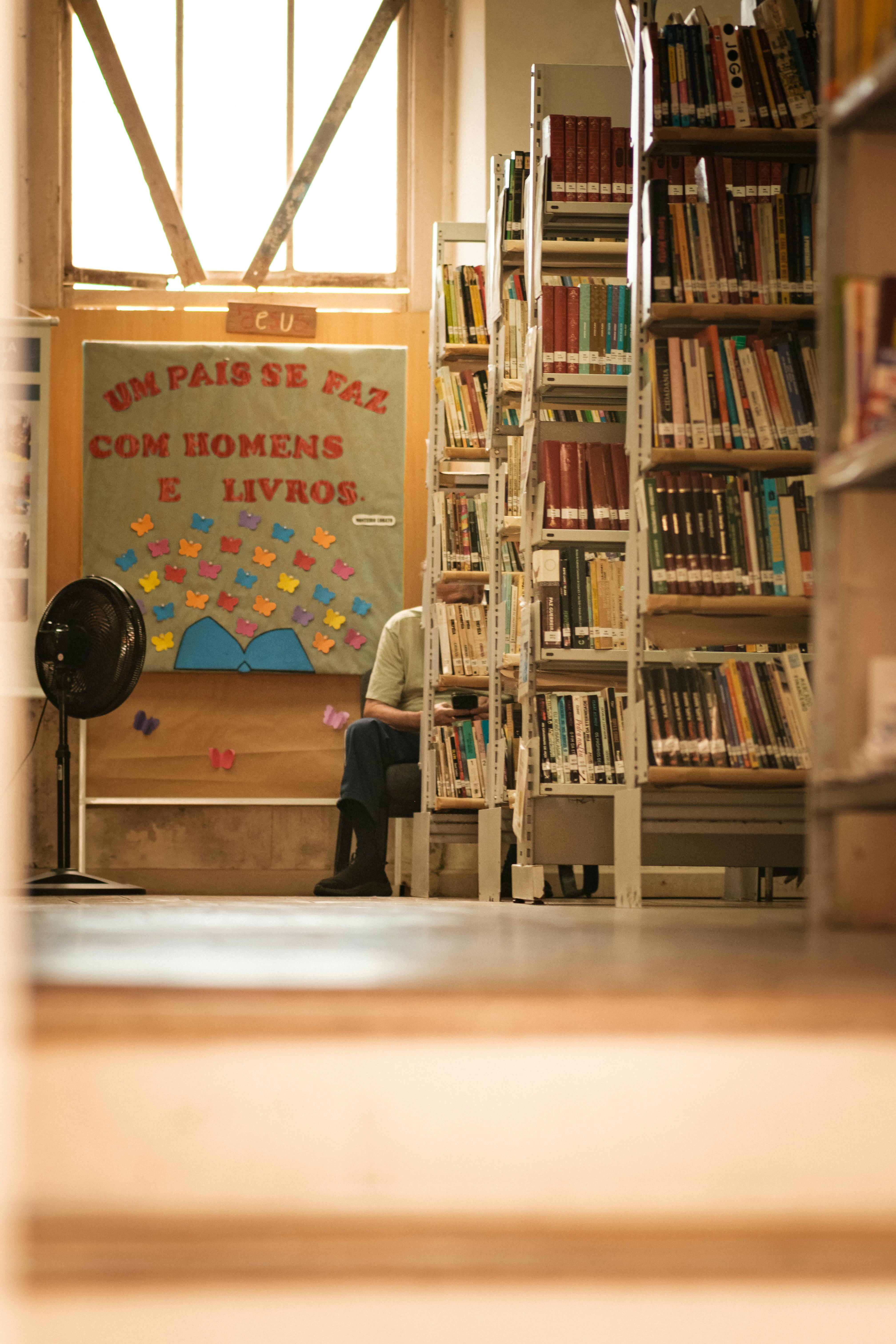 Gratis Sebuah pemandangan perpustakaan yang tenang menampilkan rak buku dan kutipan inspiratif, ideal untuk tema pendidikan. Foto Stok