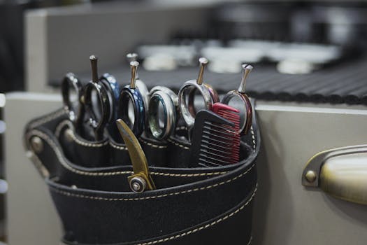 Close-up of barber tools in a leather holster, including scissors and combs, in a salon setting.