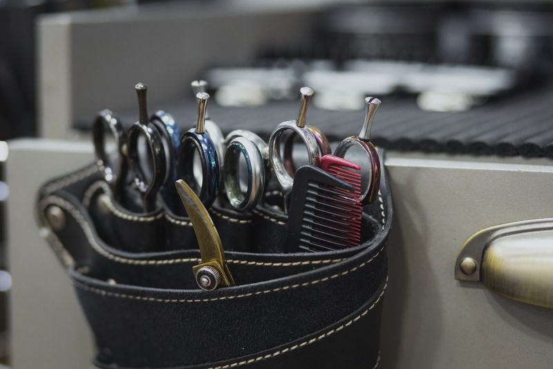 Several pairs of barber shears and a comb in a leather holster
