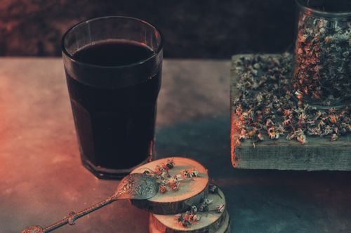 Free A moody setup of herbal tea with dried flowers and wooden coasters, perfect for a rustic and cozy atmosphere. Stock Photo