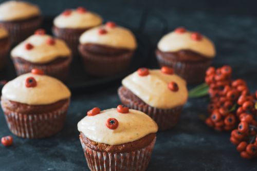 Free Close-up of cupcakes with creamy frosting and red berry decoration. Stock Photo