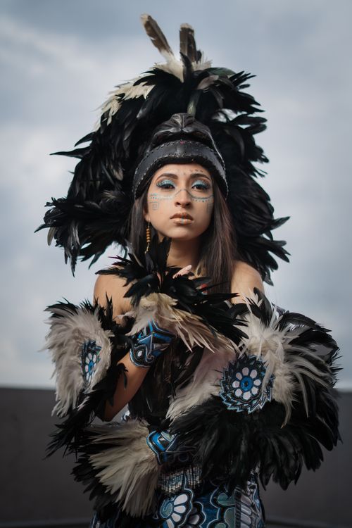 Free Portrait of a young woman wearing traditional indigenous attire with feather headpiece and face paint. Stock Photo