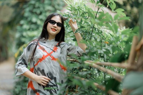 Free Stylish woman in sunglasses enjoys a sunny day in a lush garden setting. Stock Photo