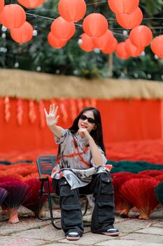 Woman in Asian festive setting with vibrant red lanterns and incense bundles.