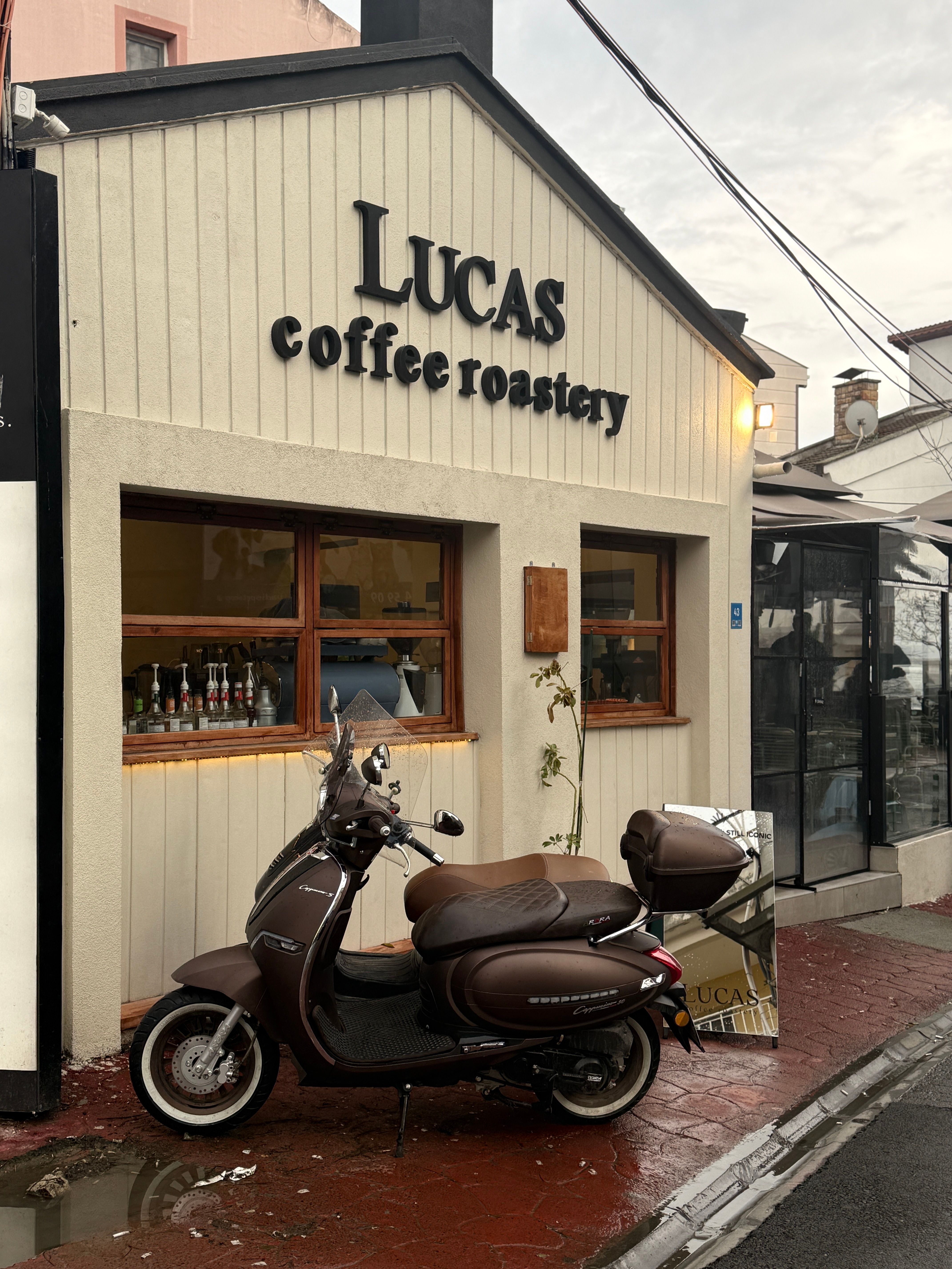 A cozy coffee roastery with vintage scooter parked outside, exuding warmth and charm.