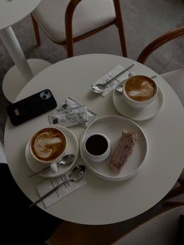 Top view of a minimalist coffee table with cappuccinos and dessert, creating a warm and inviting ambiance.