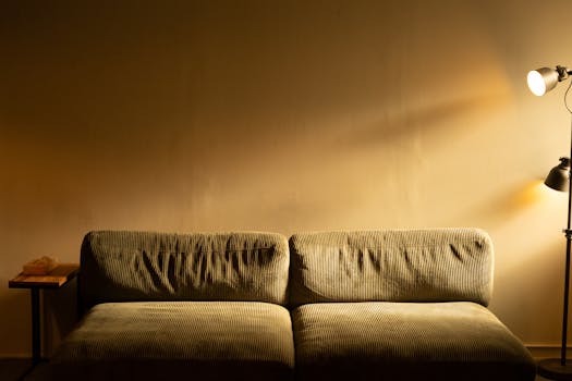 Warmly lit living room featuring a comfortable sofa and a floor lamp casting a soft glow.