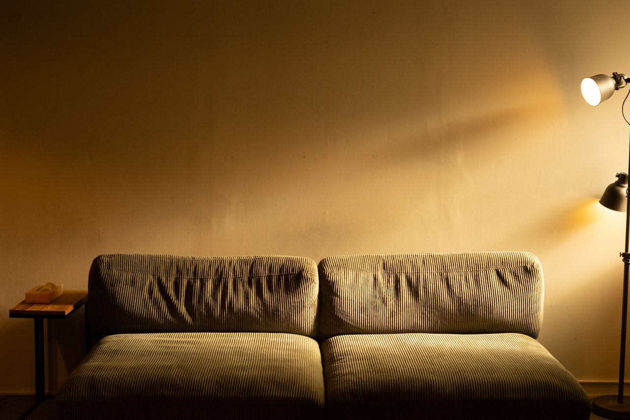 A corduroy sofa lit by a single floor lamp in a warm, low-lit room — photo by Josh Sorenson on Pexels
