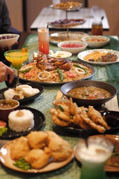 Delicious spread of Indonesian food with sate, rice, and vibrant drinks on a festive table setting.