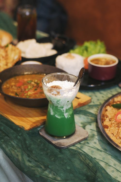 Free A vibrant spread of Indonesian cuisine featuring green drink and various dishes, perfect for festive occasions. Stock Photo