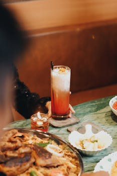 A cozy dining setup featuring traditional Indonesian food and a refreshing drink.