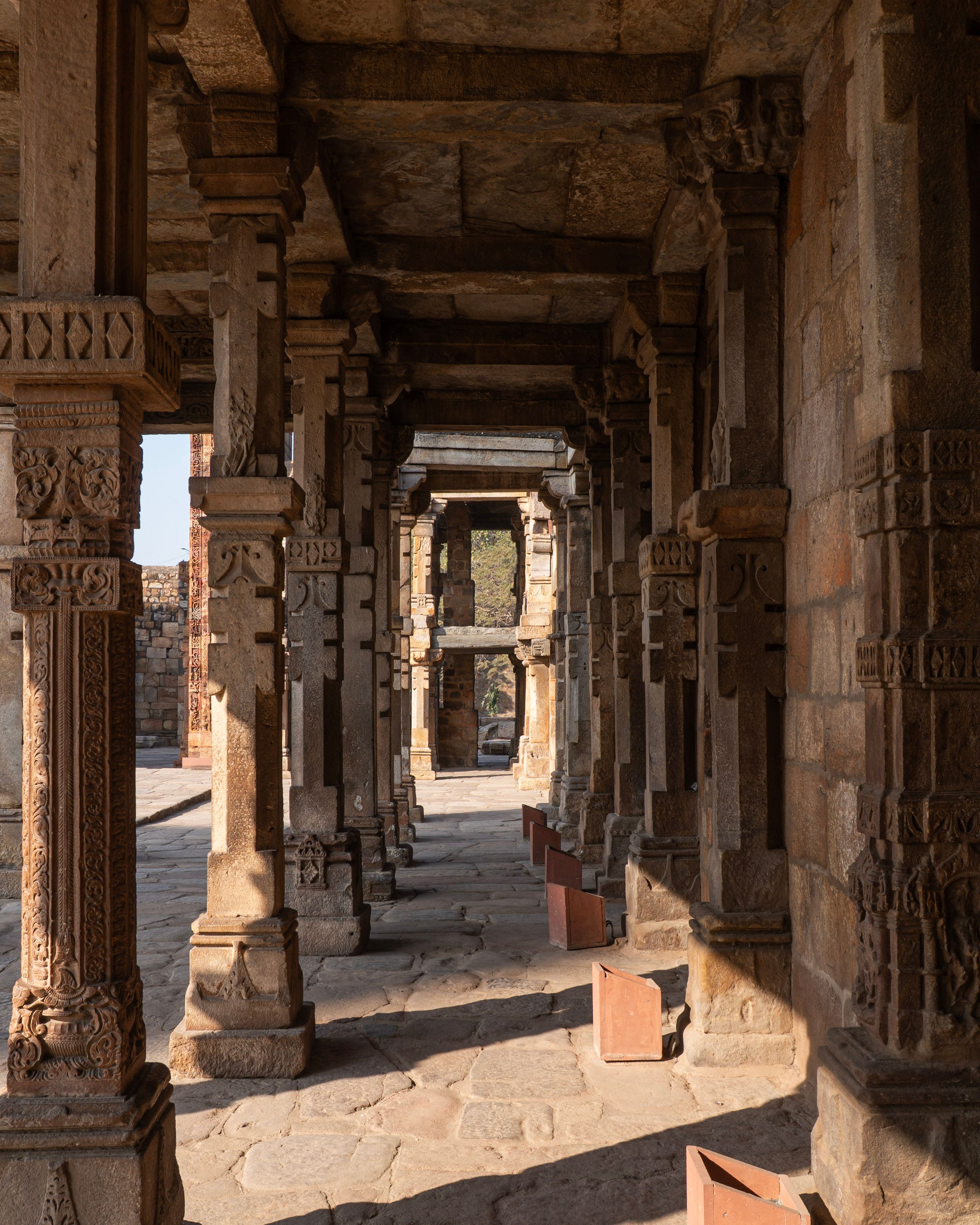 Ancient stone pillars and arches within the Quwwatu'l-Islam mosque area of the Qutb Minar complex, India.