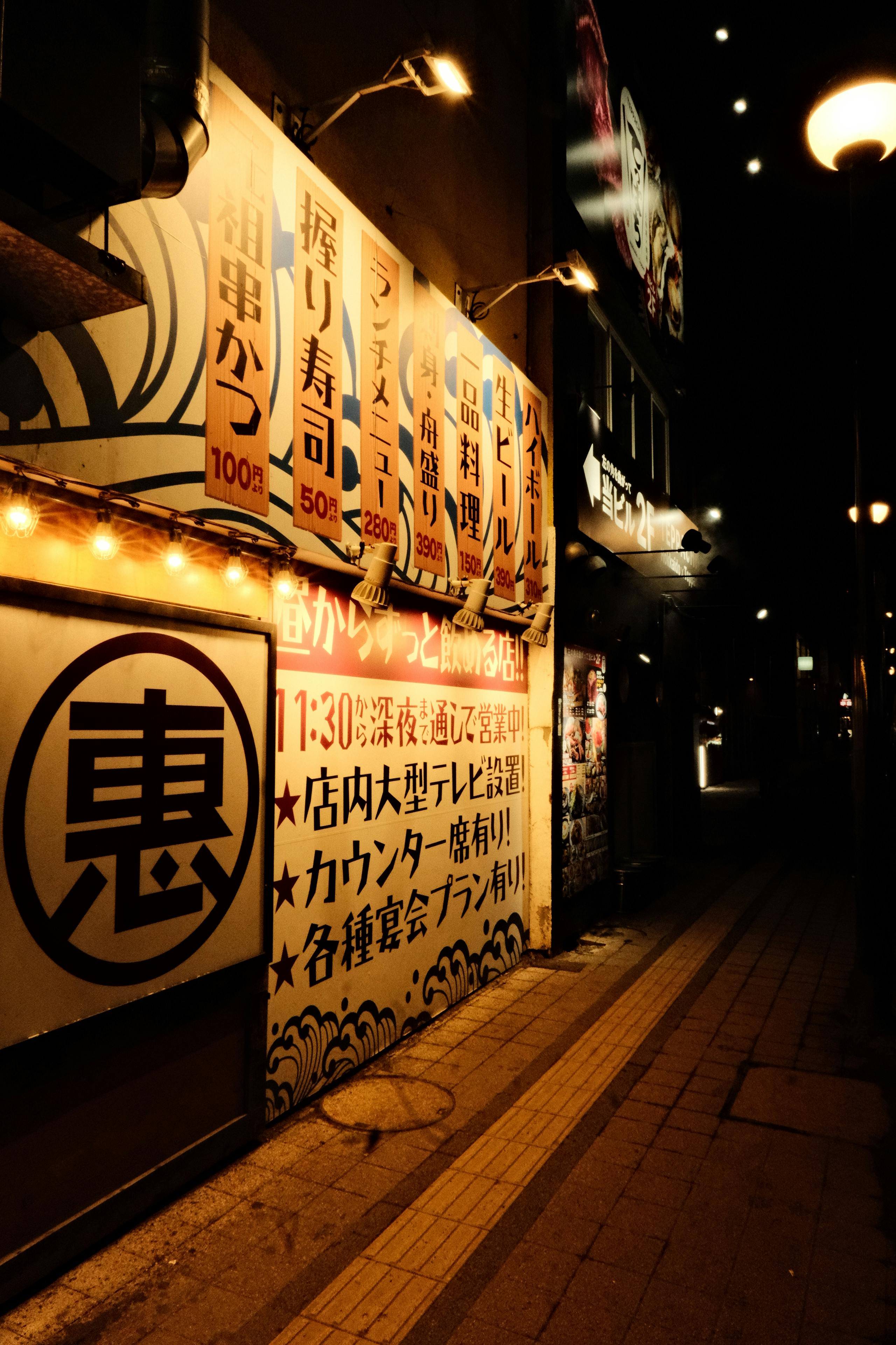 бесплатная Ночная японская улица с подсвеченными неоновыми вывесками и традиционными указателями. Стоковое фото