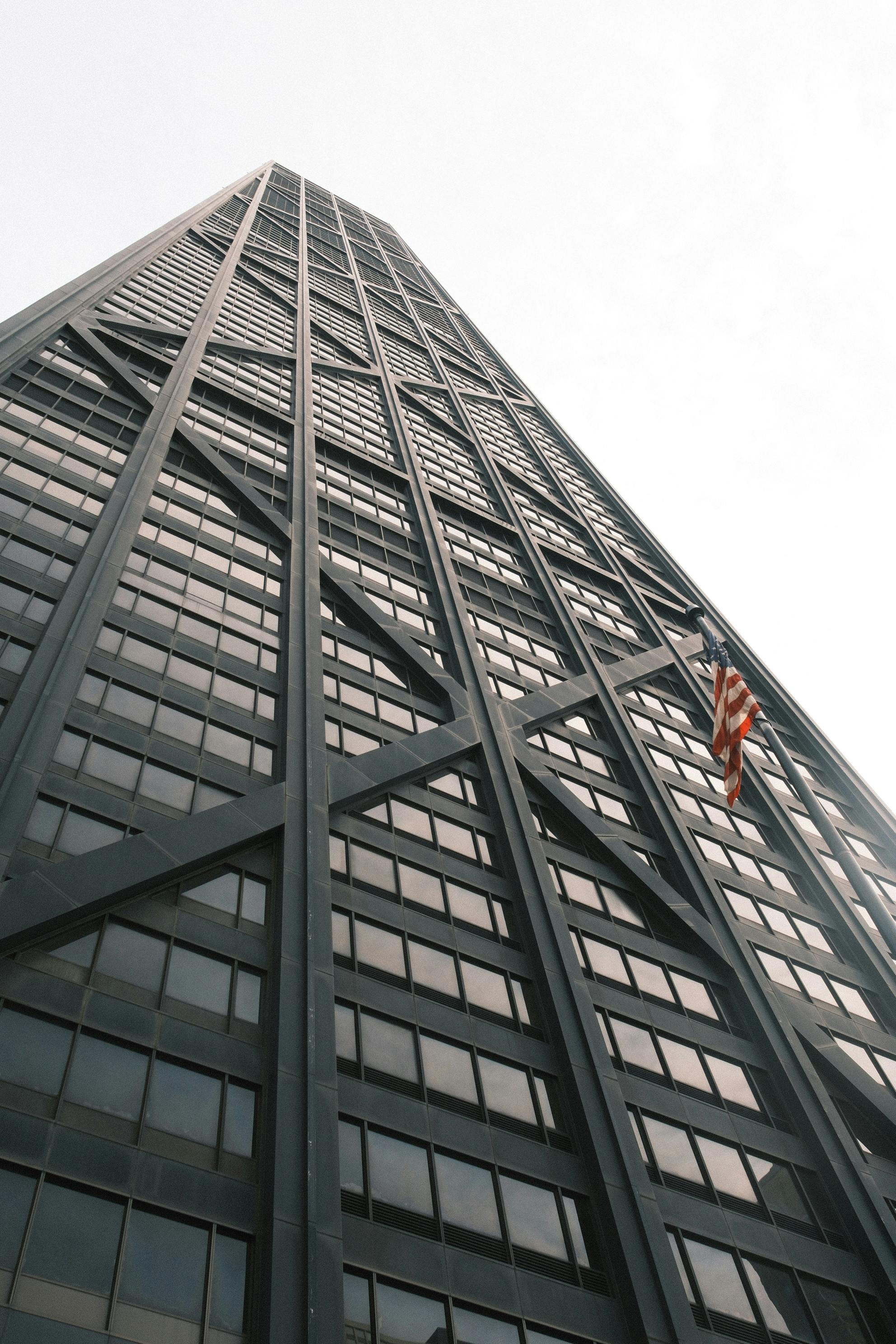 Gratis Lavvinkelvisning av en skyskraper med stålkonstruksjon og amerikansk flagg. Arkivbilde